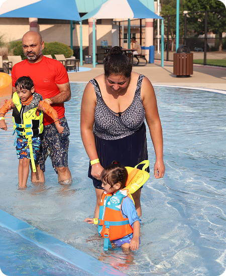 A family including Mom, Dad and their Daughters are making their day happy by enjoying the swimming pool